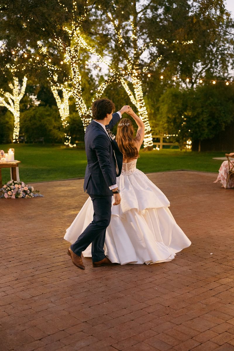 A couple dancing at their wedding reception the groom is spinning the bride who is wearing a white wedding dress the groom is wearing a suit 