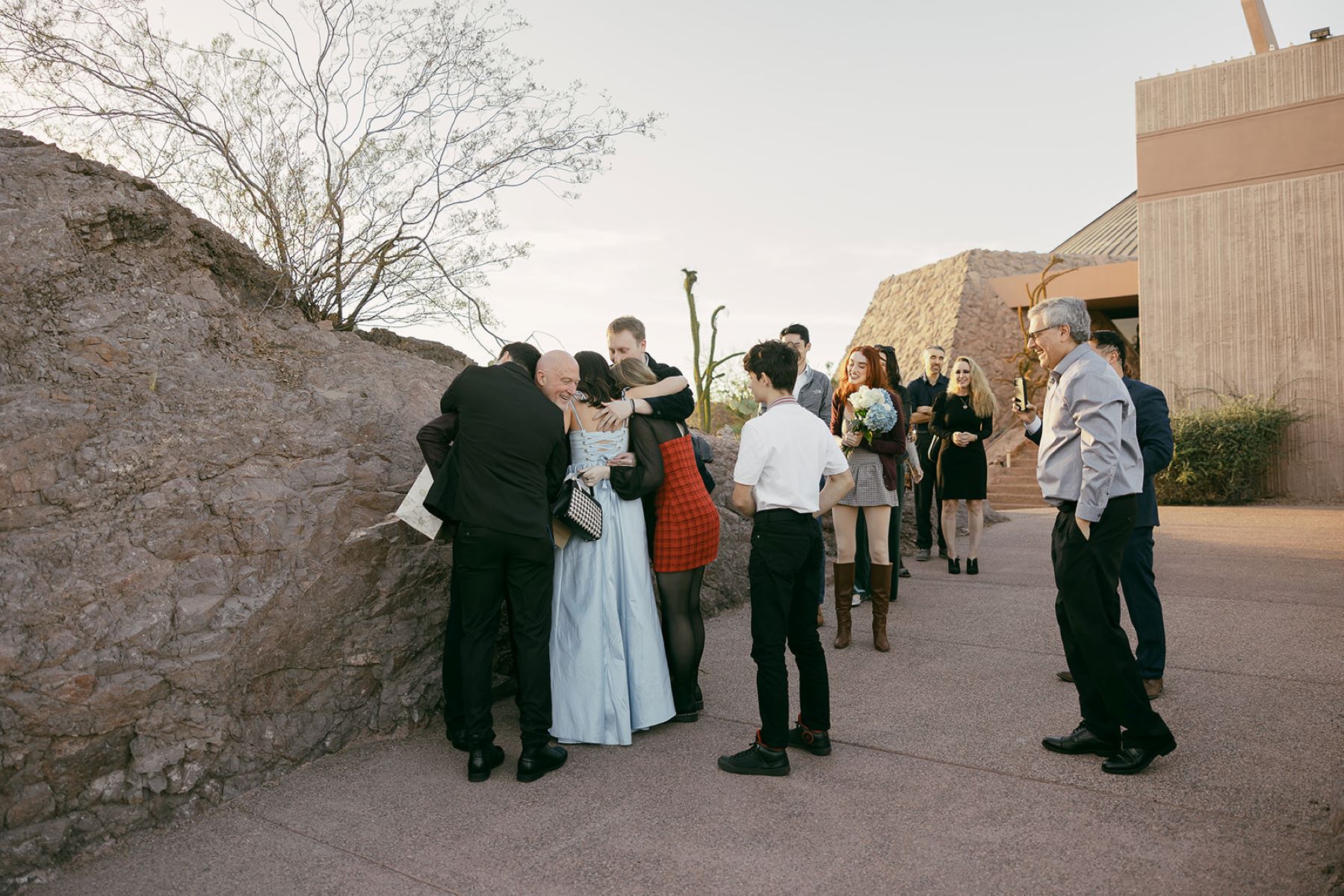 A couple celebrating with their family their recent engagement they are hugging and laughing each other while other family members cheer them on 