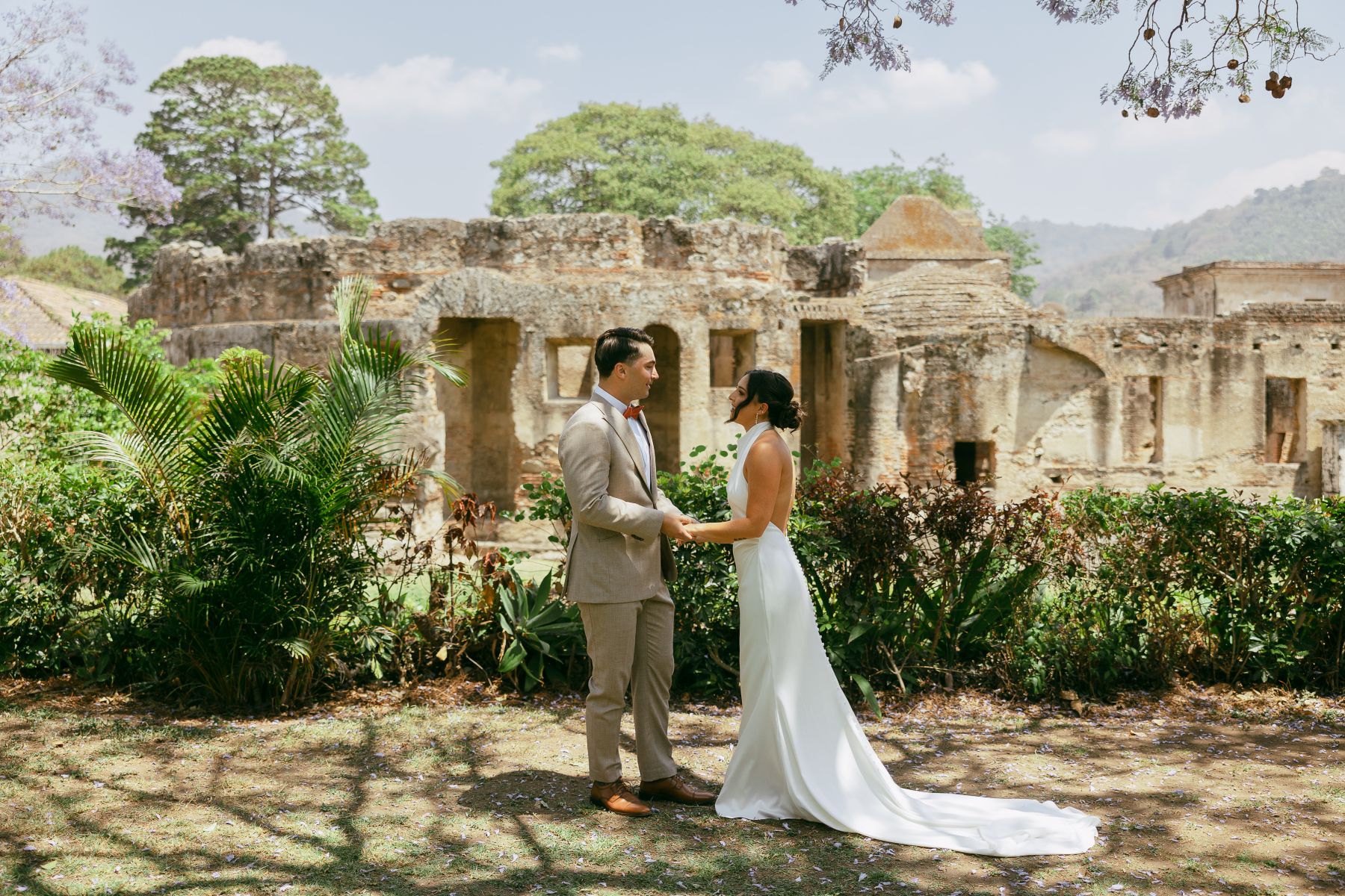 a couple having their wedding in antigua guatemala at convento capuchinas they are standing in front of the ruins smiling at each other and holding hands