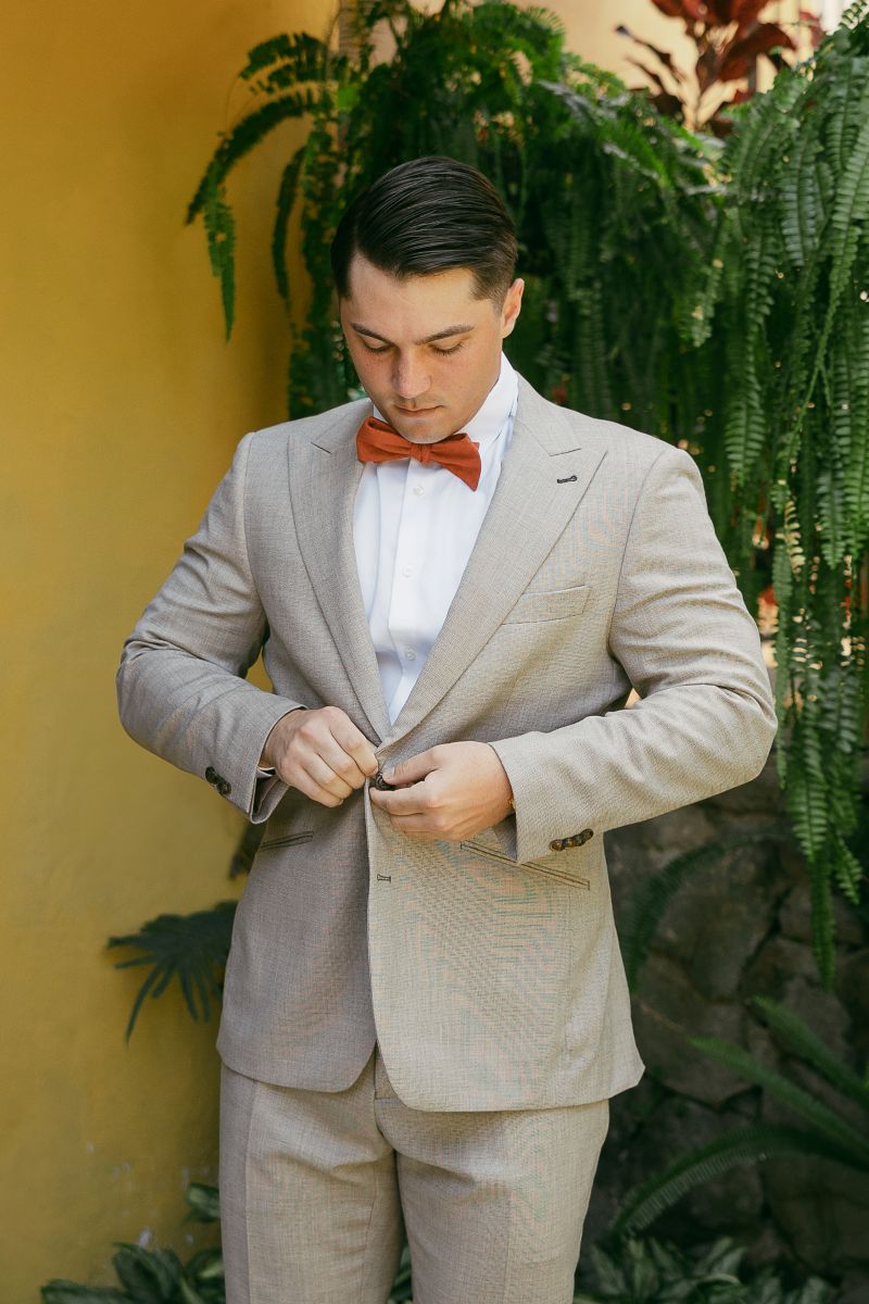 a man in a gray suit buttoning his shirt coat