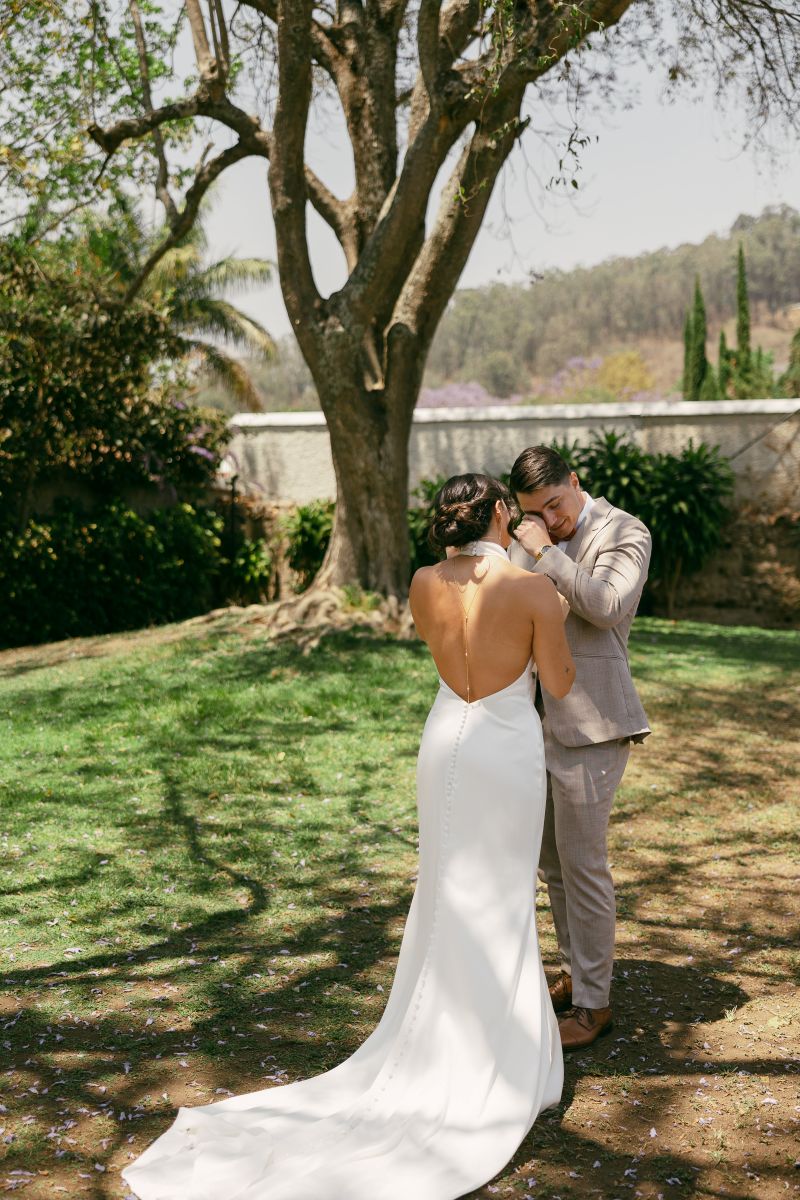 a man and woman sharing a first look on their wedding day the man is wiping a tear from his eye